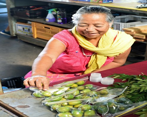 Woman holding fresh vegetables smiling in a kitchen setting